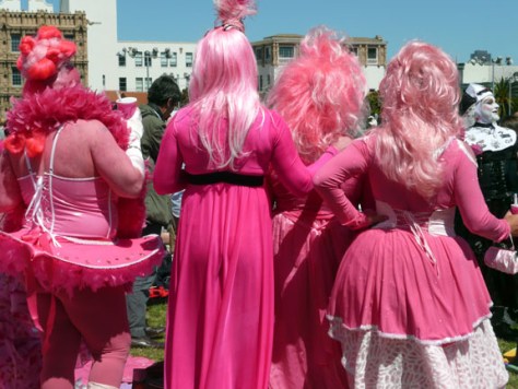 backsides of 4 men dressed in pink dresses with pink hair
