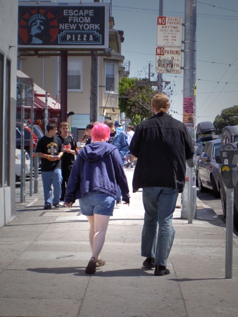 couple walking on Haight Street; woman has pink hair and white legs