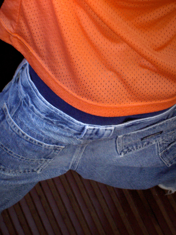 Skinny butt in blue jeans and orange shirt 