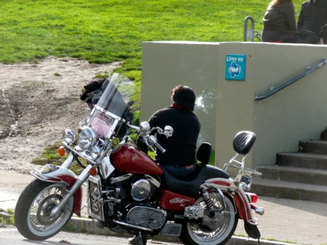Man smoking on parked motorcycle on Dolores Street in San Francisco